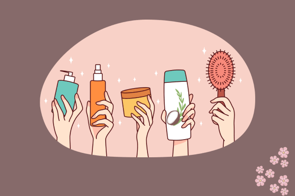 The image depicts a collection of hair care products being held up by hands. The products include a teal pump bottle, an orange spray bottle, a brown jar, a white bottle with a green cap, and a red hairbrush. The background is a light pink oval shape with a darker pink border and small white flower designs in the bottom right corner. The hands holding the products are drawn in a simple, cartoonish style. These products are likely intended for hair care, possibly including shampoo, conditioner, styling products, and a brush.